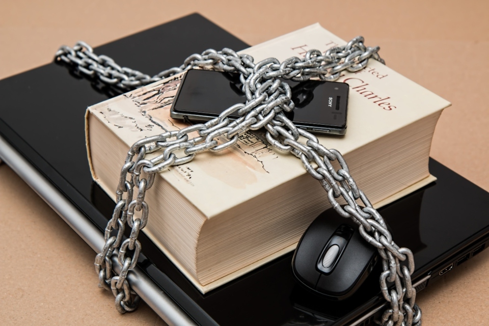 a computer, a book and a phone protected with a chain