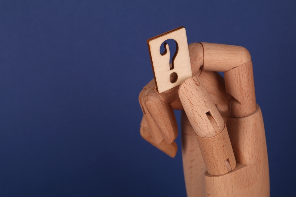 a wooden hand holding a question mark