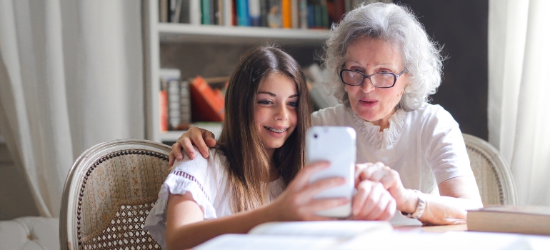 A girl and an old woman looking at the cell phone