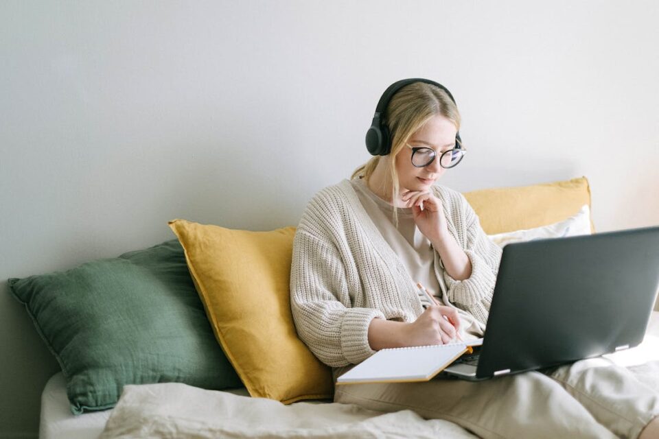 A young woman looking at her laptop and writing something